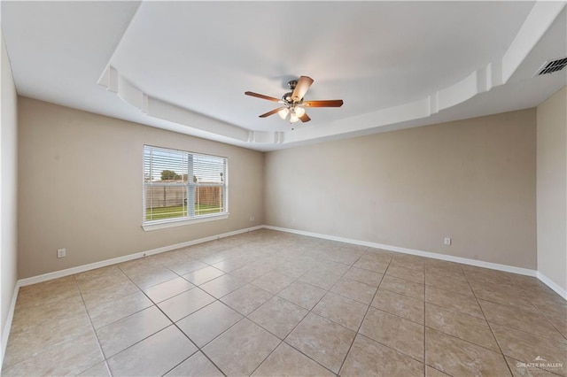 unfurnished room with a raised ceiling, light tile patterned floors, and ceiling fan