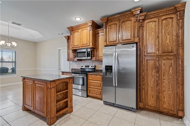 kitchen with a kitchen island, appliances with stainless steel finishes, tasteful backsplash, a chandelier, and light tile patterned floors