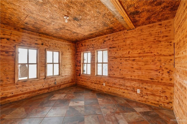 unfurnished room featuring beam ceiling and wood walls