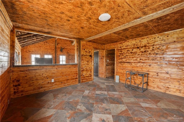 unfurnished room featuring wood walls and lofted ceiling