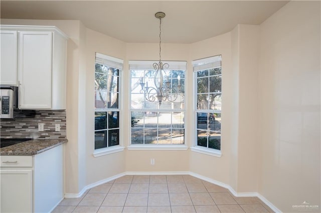 unfurnished dining area featuring light tile patterned floors and an inviting chandelier