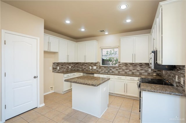 kitchen with a center island, white cabinetry, and dark stone counters