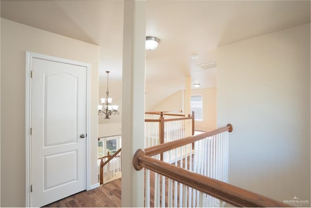 hall with wood-type flooring and an inviting chandelier