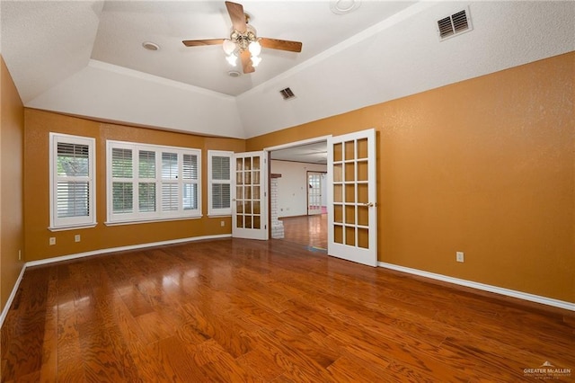 unfurnished room with vaulted ceiling, wood-type flooring, ceiling fan, a raised ceiling, and french doors