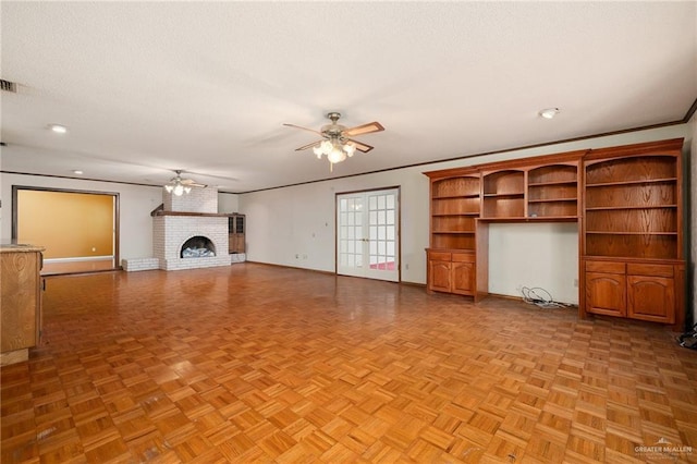 unfurnished living room featuring a brick fireplace, light parquet floors, ornamental molding, and ceiling fan