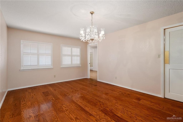 empty room with an inviting chandelier and dark hardwood / wood-style flooring