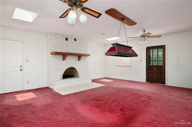 unfurnished living room featuring ceiling fan, carpet, a fireplace, and a skylight