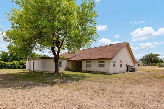 rear view of property with a lawn and central air condition unit