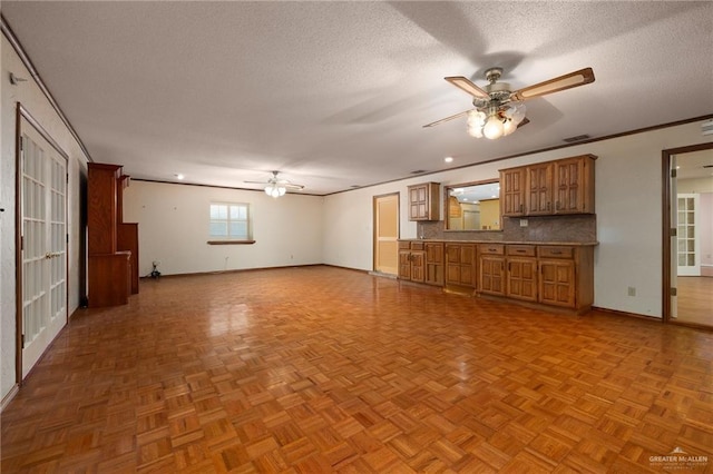 unfurnished living room with crown molding, ceiling fan, light parquet flooring, and a textured ceiling