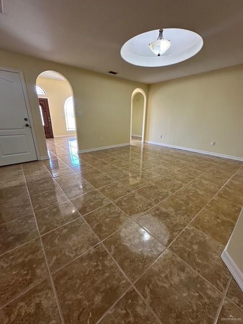 1502 W Kennedy Ave, Alton, TX 78573 - empty room with arched walkways, dark tile patterned flooring, and baseboards