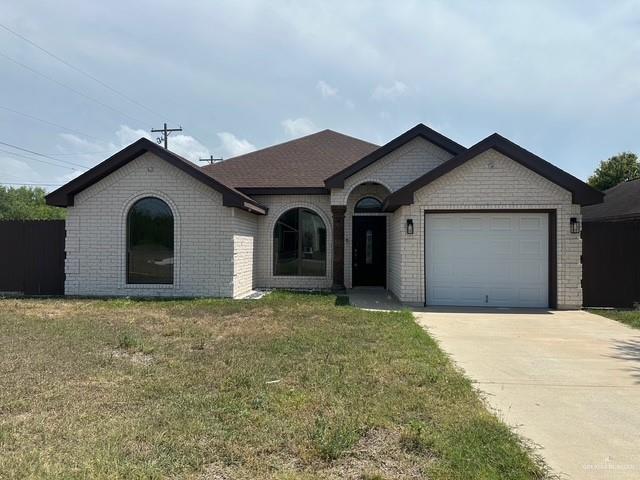 1502 W Kennedy Ave, Alton, TX 78573 - french provincial home with brick siding, a garage, concrete driveway, and a front lawn