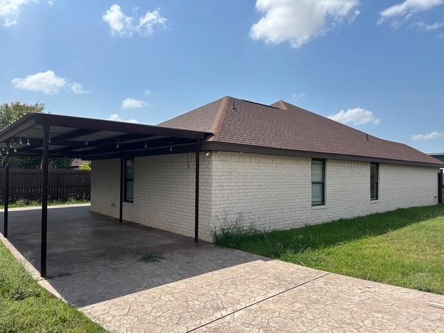 1502 W Kennedy Ave, Alton, TX 78573 - view of home's exterior with driveway, a carport, brick siding, and a shingled roof