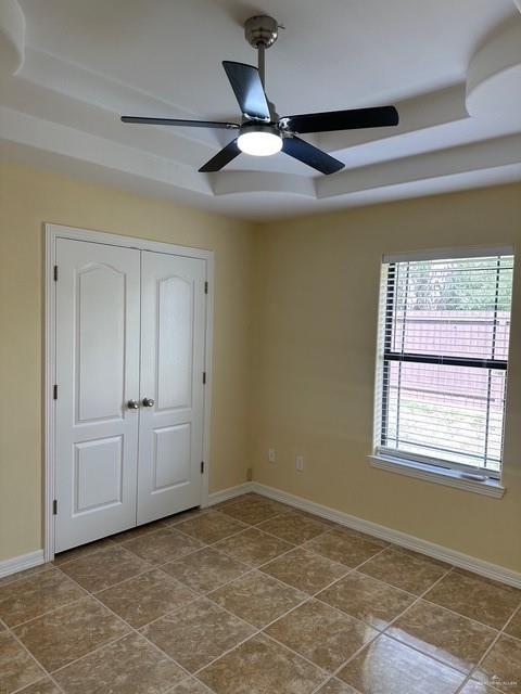 1502 W Kennedy Ave, Alton, TX 78573 - unfurnished bedroom with baseboards, a closet, a ceiling fan, and dark tile patterned floors