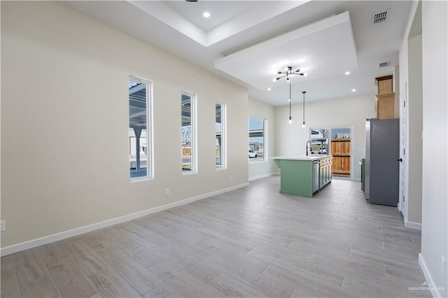 kitchen with light wood finished floors, baseboards, visible vents, and freestanding refrigerator