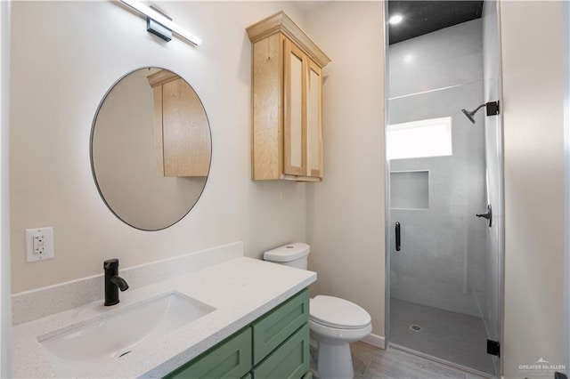 bathroom with a stall shower, vanity, and toilet