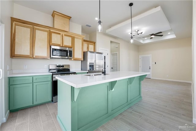 kitchen with visible vents, a tray ceiling, stainless steel appliances, light countertops, and a sink