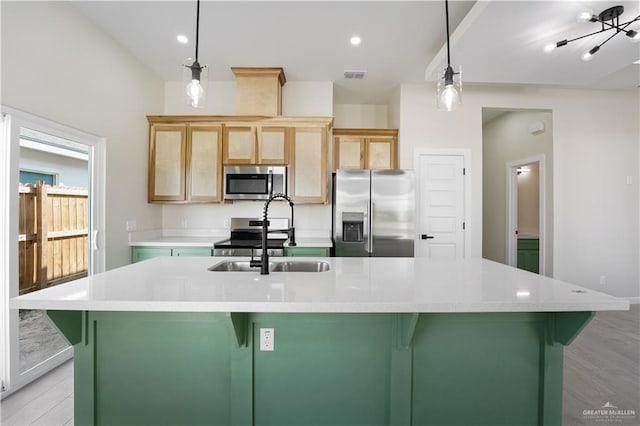 kitchen with stainless steel appliances, a spacious island, light countertops, a sink, and light wood-type flooring