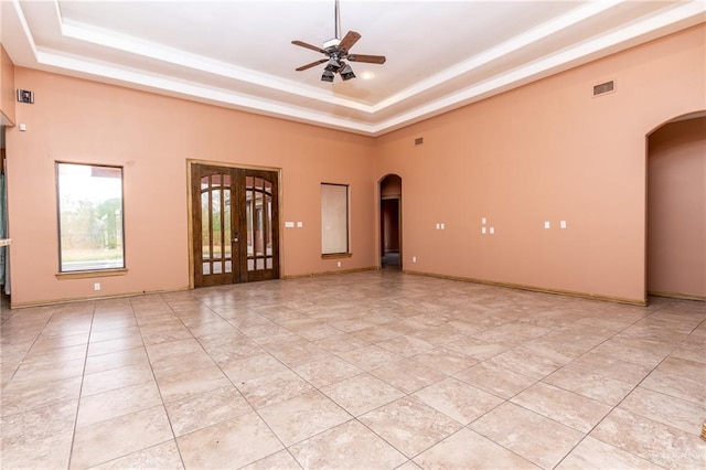 tiled empty room featuring a raised ceiling and ceiling fan