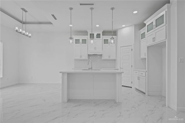 kitchen with a sink, tasteful backsplash, marble finish floor, and light countertops