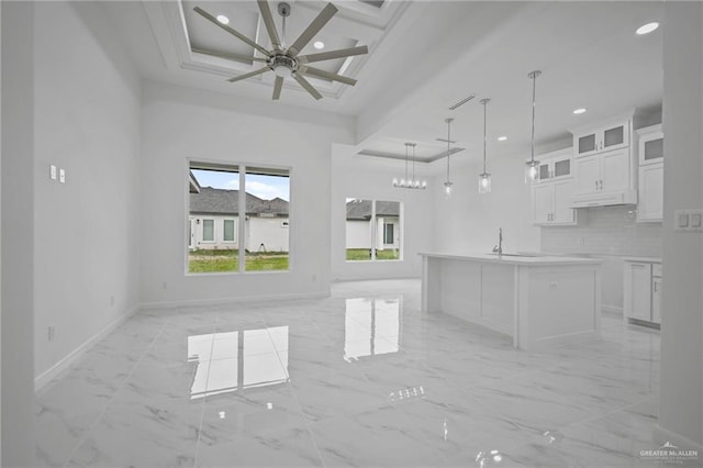 kitchen featuring backsplash, baseboards, open floor plan, white cabinets, and marble finish floor