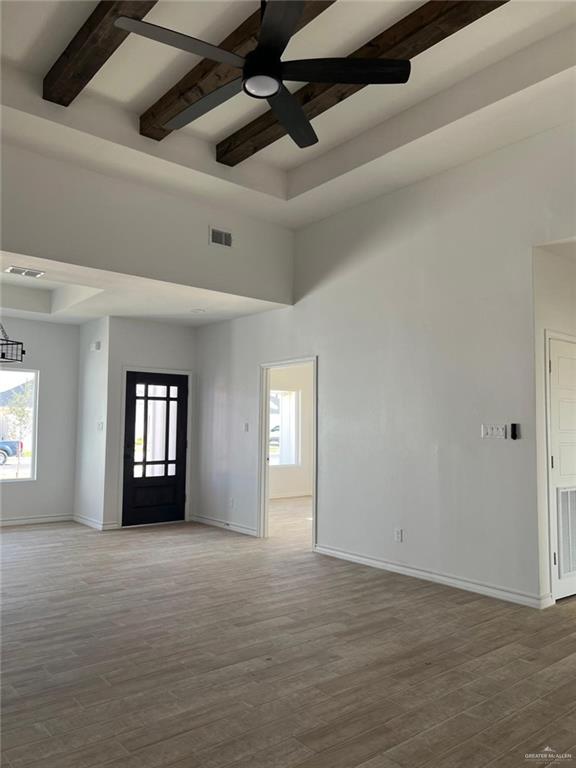 spare room featuring ceiling fan, wood-type flooring, and a wealth of natural light