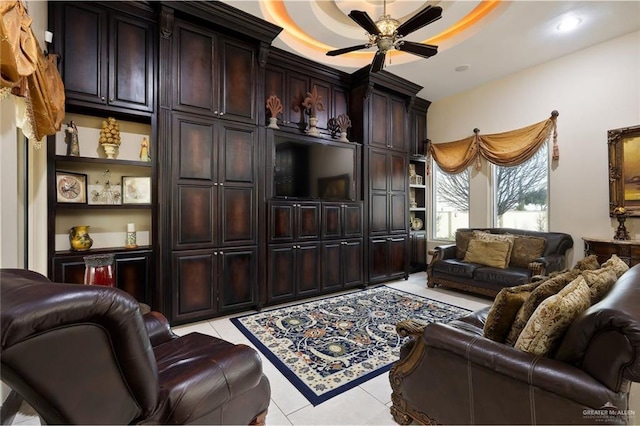 living room with light tile patterned floors, a tray ceiling, and a ceiling fan