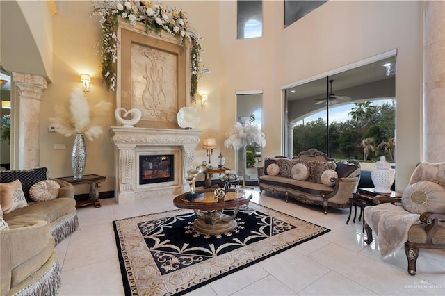 living area with light tile patterned floors, decorative columns, a premium fireplace, and a high ceiling