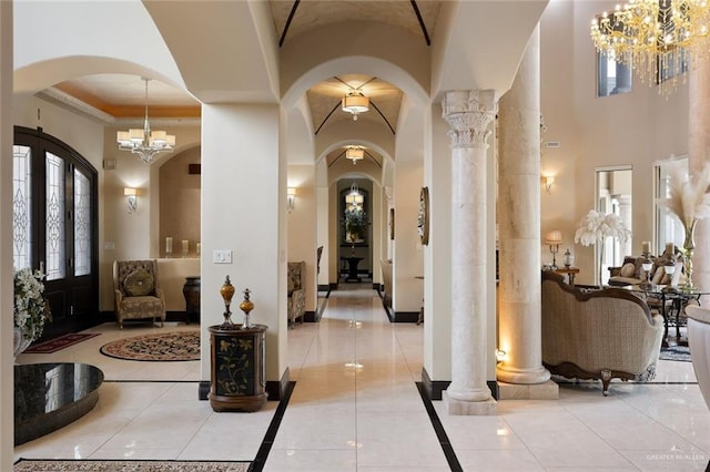 entryway with an inviting chandelier, decorative columns, light tile patterned floors, and arched walkways