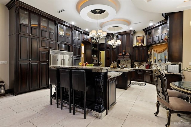 kitchen featuring a center island, stainless steel appliances, hanging light fixtures, glass insert cabinets, and dark brown cabinetry