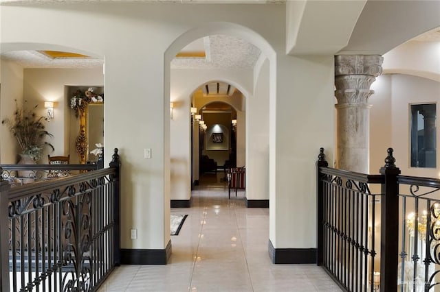 hall with a textured ceiling, tile patterned flooring, and baseboards