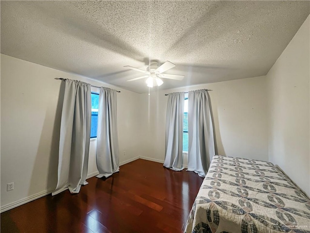 bedroom featuring ceiling fan, dark wood-type flooring, and a textured ceiling