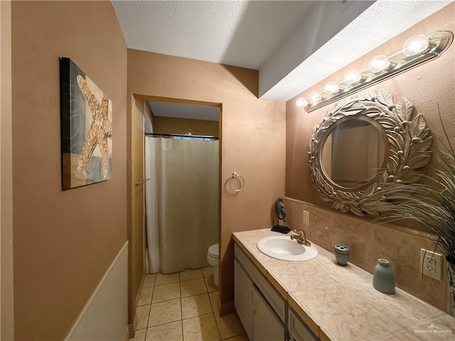 bathroom with toilet, vanity, tile patterned flooring, backsplash, and a textured ceiling