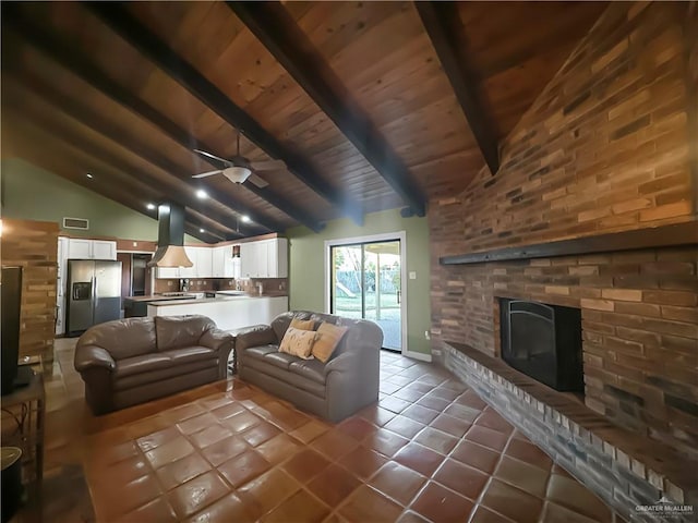 living room with wood ceiling, ceiling fan, a fireplace, dark tile patterned flooring, and beam ceiling