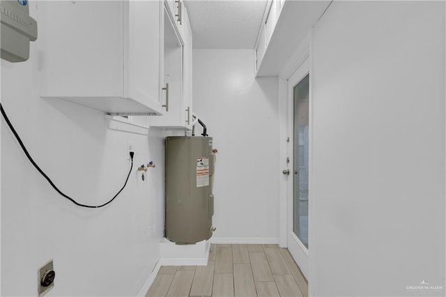 clothes washing area with cabinets, a textured ceiling, light hardwood / wood-style flooring, hookup for a washing machine, and electric water heater