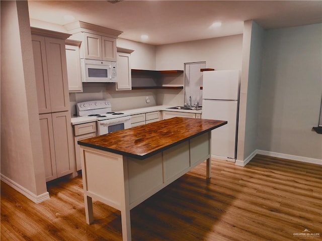 kitchen with a kitchen bar, sink, dark hardwood / wood-style floors, a kitchen island, and white appliances