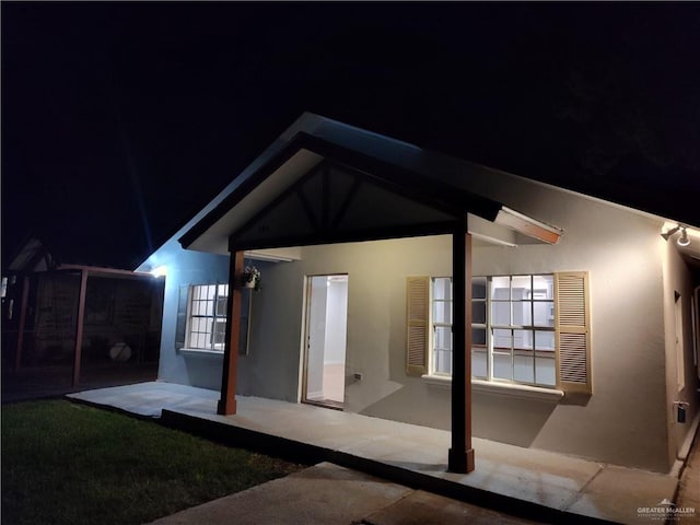 back house at twilight featuring a patio