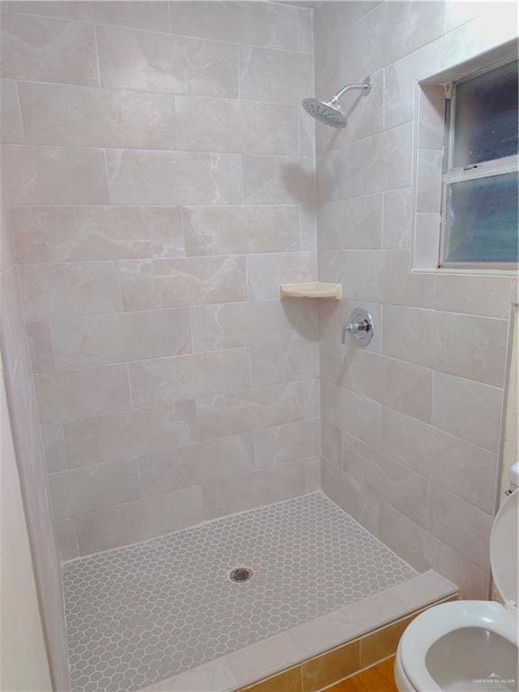 bathroom with tiled shower and toilet