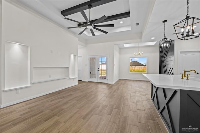 unfurnished living room with ceiling fan with notable chandelier and light hardwood / wood-style floors