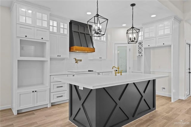 kitchen featuring a center island with sink, light wood-type flooring, white cabinetry, and custom range hood