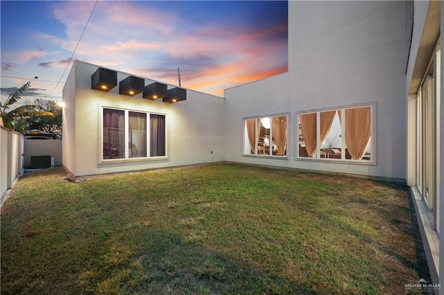 back house at dusk with a lawn