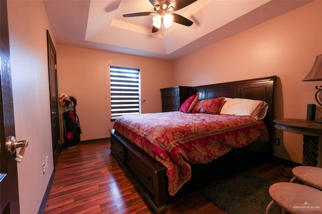 bedroom featuring a tray ceiling, ceiling fan, and dark hardwood / wood-style flooring