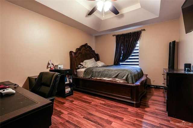 bedroom featuring dark hardwood / wood-style floors, a raised ceiling, and ceiling fan