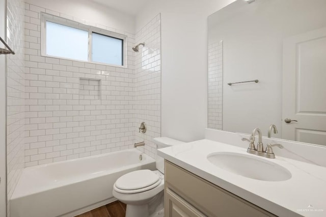 full bathroom featuring vanity, hardwood / wood-style floors, tiled shower / bath combo, and toilet