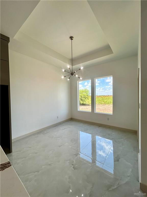 514 Oriole Dr, Los Fresnos, TX 78566 - empty room with a raised ceiling, a chandelier, and concrete floors