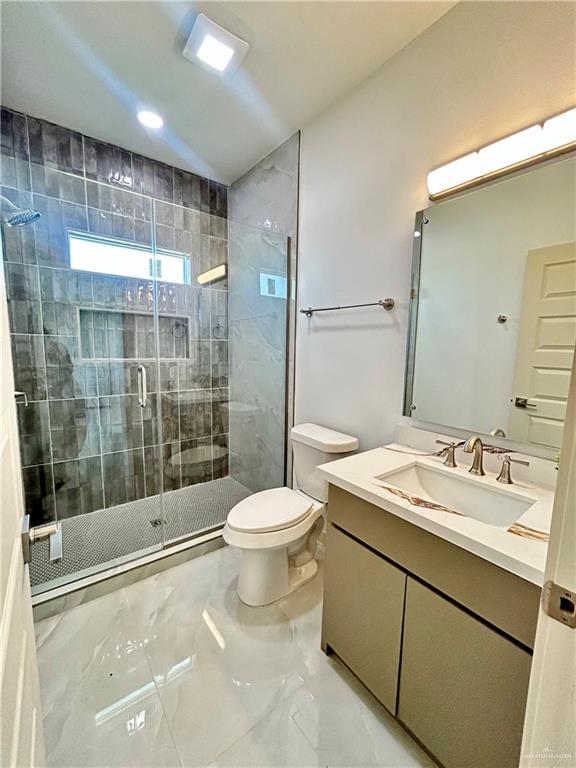 514 Oriole Dr, Los Fresnos, TX 78566 - bathroom featuring marble tiled flooring, vanity, and a stall shower