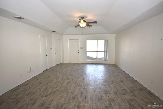 interior space with a raised ceiling, vaulted ceiling, dark hardwood / wood-style floors, and ceiling fan