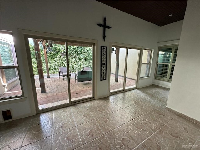 doorway to outside featuring baseboards, wooden ceiling, stone finish floor, and vaulted ceiling