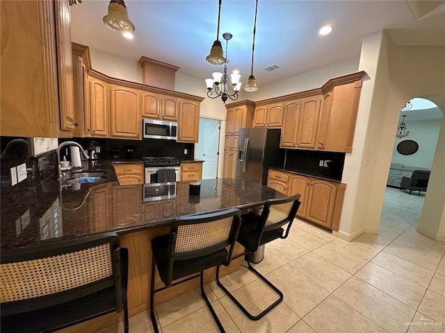 kitchen featuring a sink, visible vents, stainless steel appliances, an inviting chandelier, and a peninsula