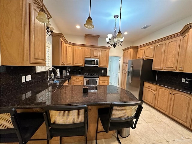 kitchen featuring light tile patterned floors, a sink, appliances with stainless steel finishes, visible vents, and a peninsula
