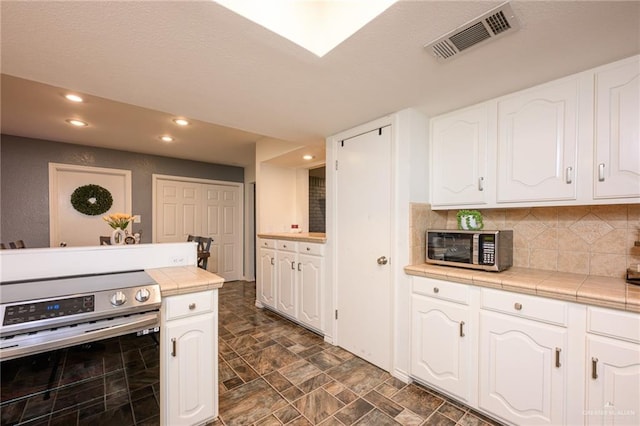 2405 E Lazy Lake Dr, Harlingen, TX 78550 - kitchen with stainless steel appliances, tile counters, recessed lighting, white cabinetry, and dark stone finish floors